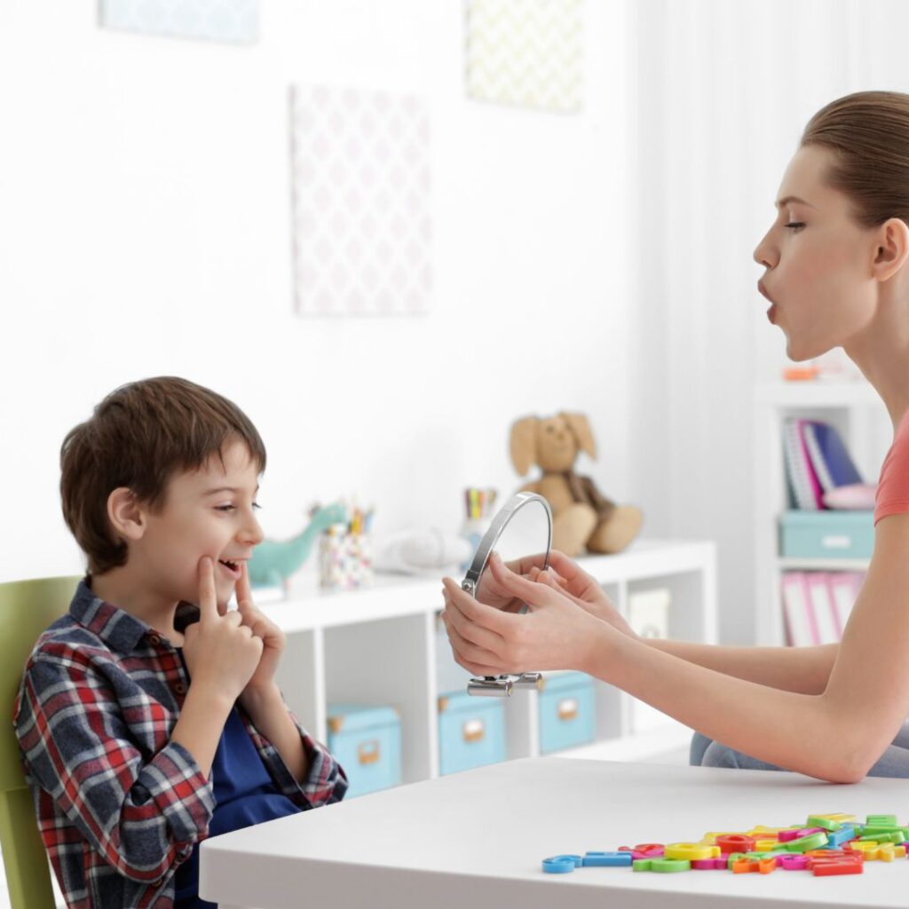 Speech Therapist holding up mirror for boy as he shapes his mouth