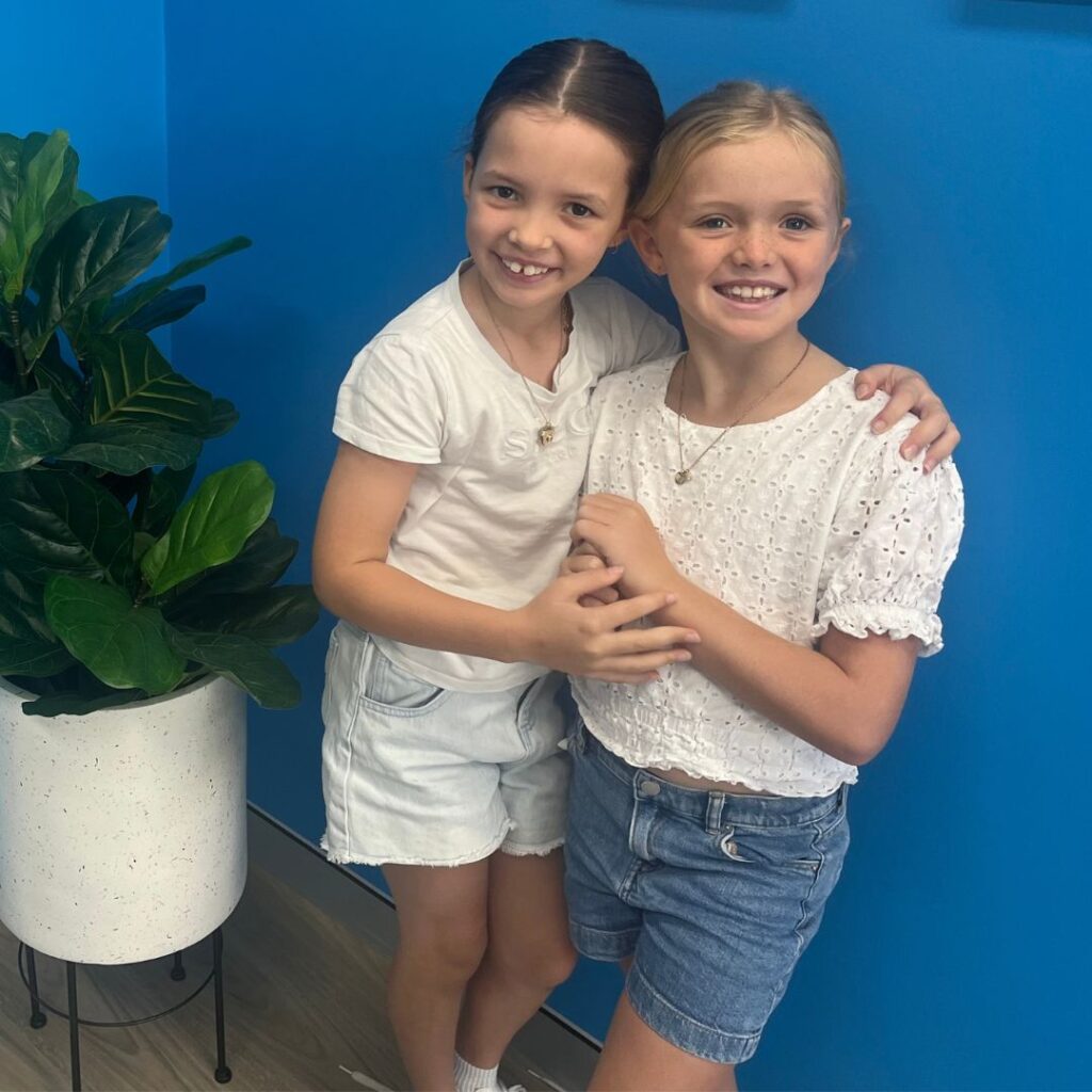 Two young girls who are participating in group therapy at QPAH hugging.