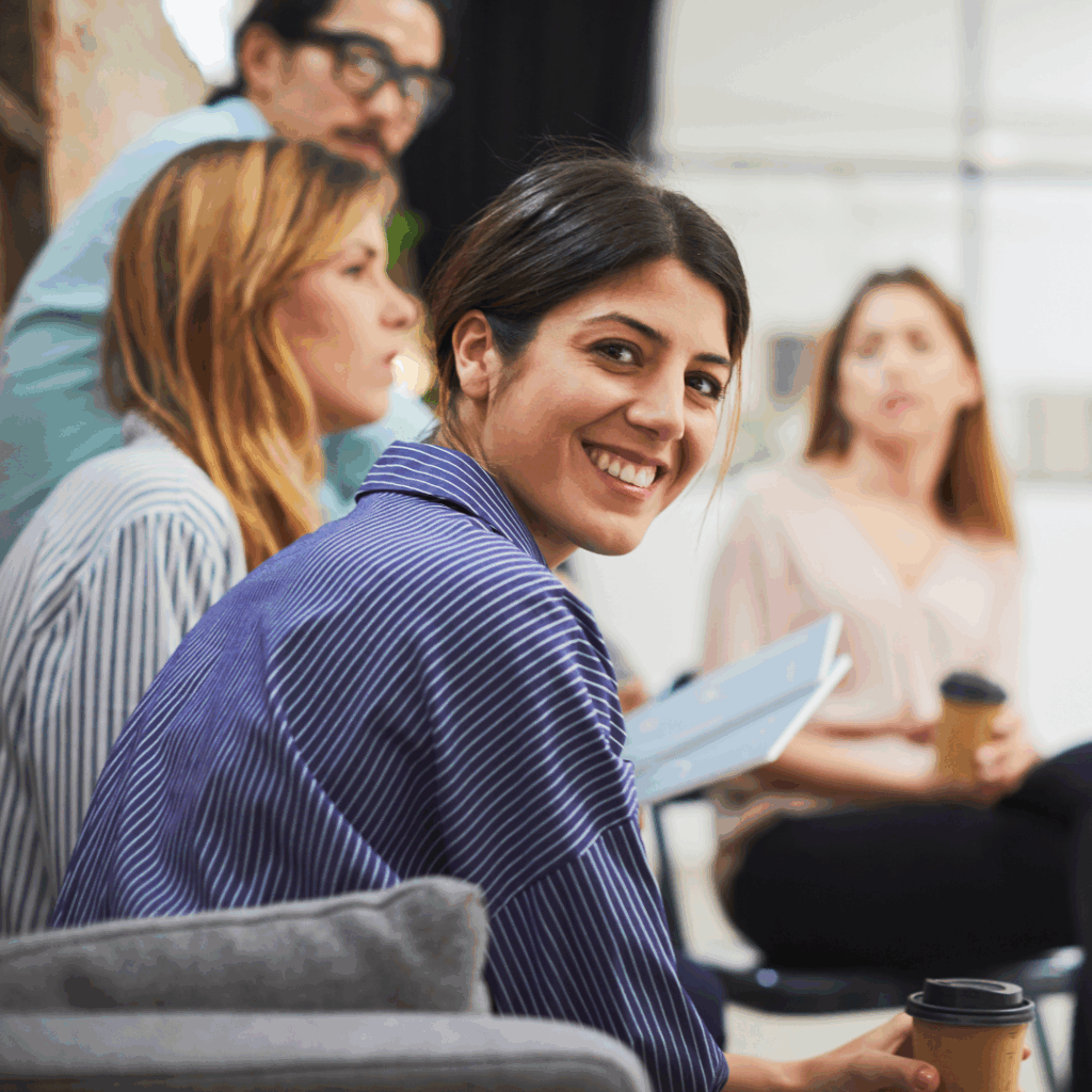 An adult man and three women sitting together - a woman is looking at the camera and smiling.